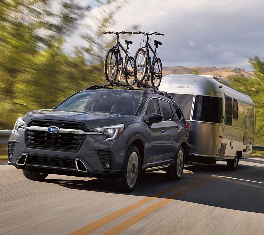 2024 Subaru Ascent towing a travel trailer with bikes on the roof rack