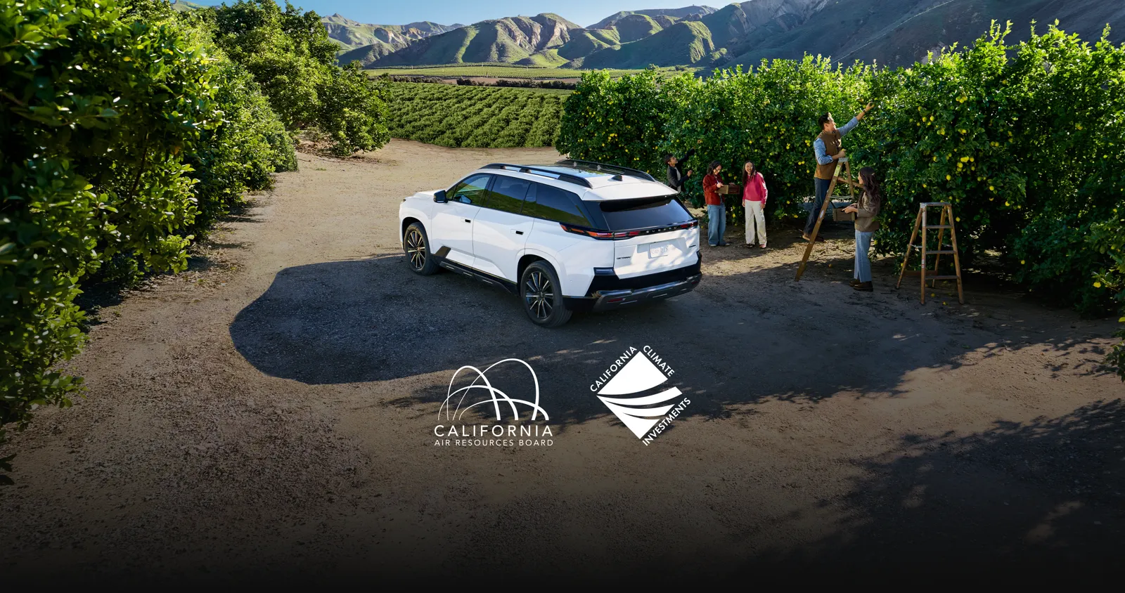 A white Subaru Getaway EV parked next to people picking fruit in an orchard.