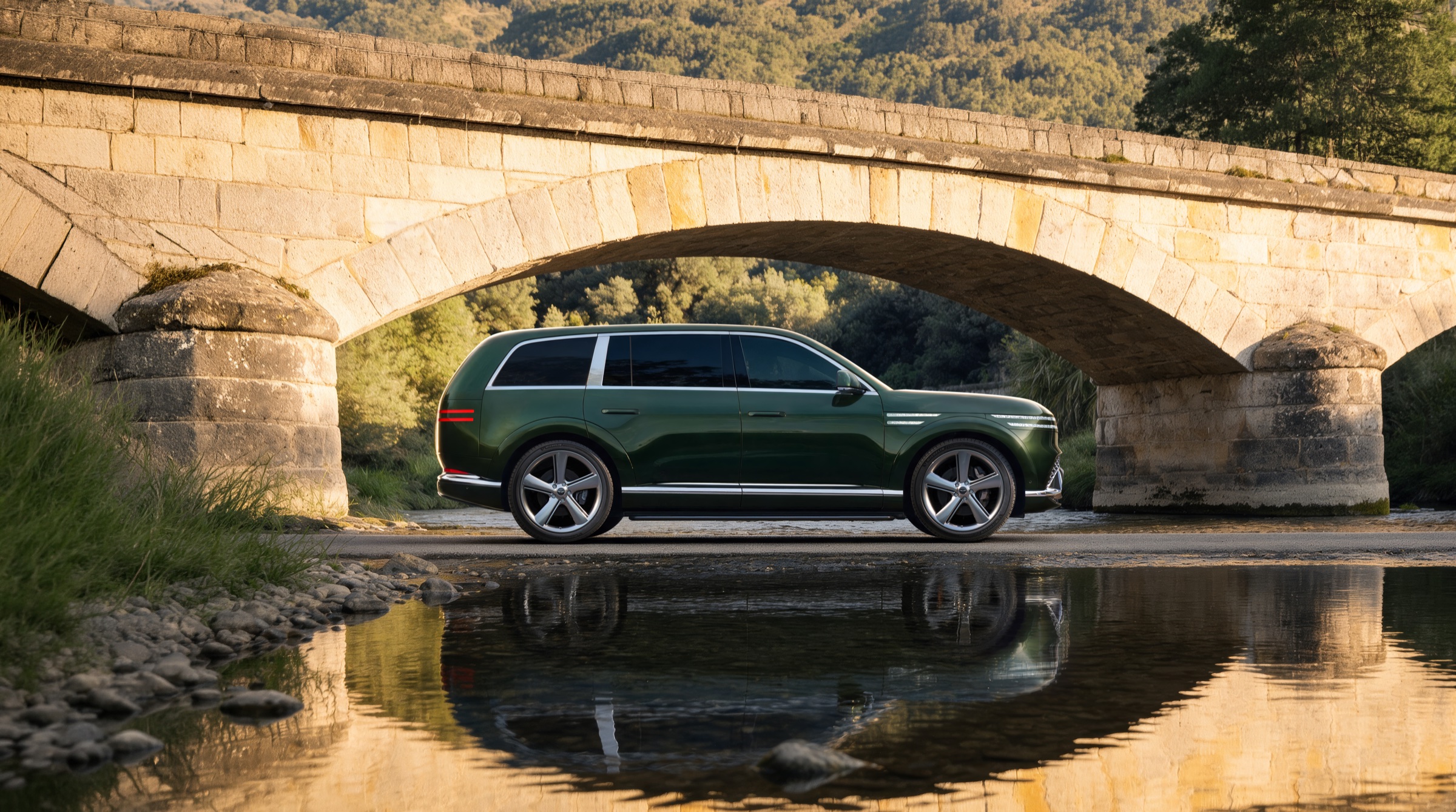 Forest green GV90 in side profile under a stone arch bridge, reflected in still water