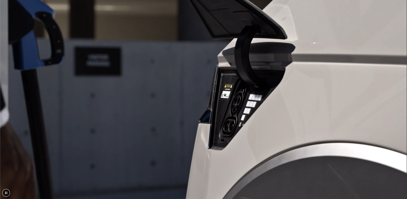 Charging port open on a white Hyundai electric vehicle beside a charging cable