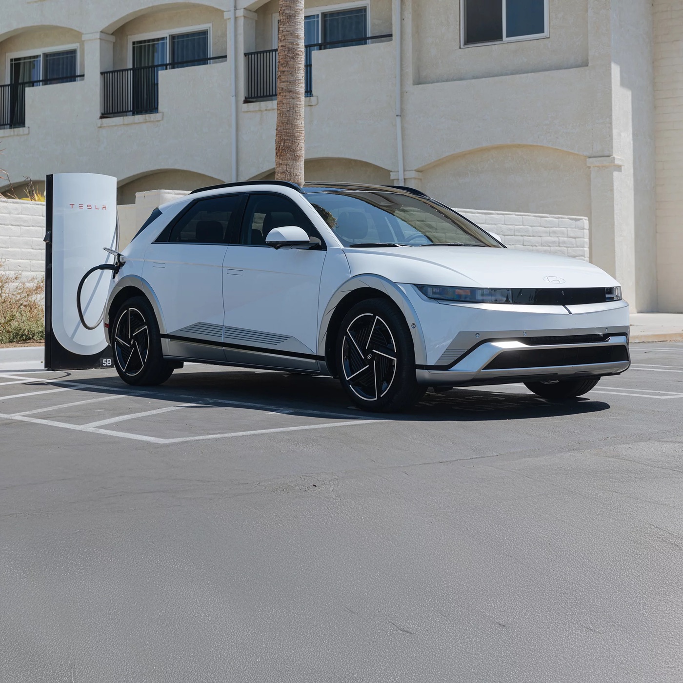 White Hyundai IONIQ 5 plugged into a Tesla Supercharger