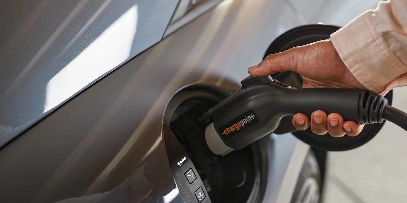 Hand plugging a ChargePoint connector into a Hyundai charging port