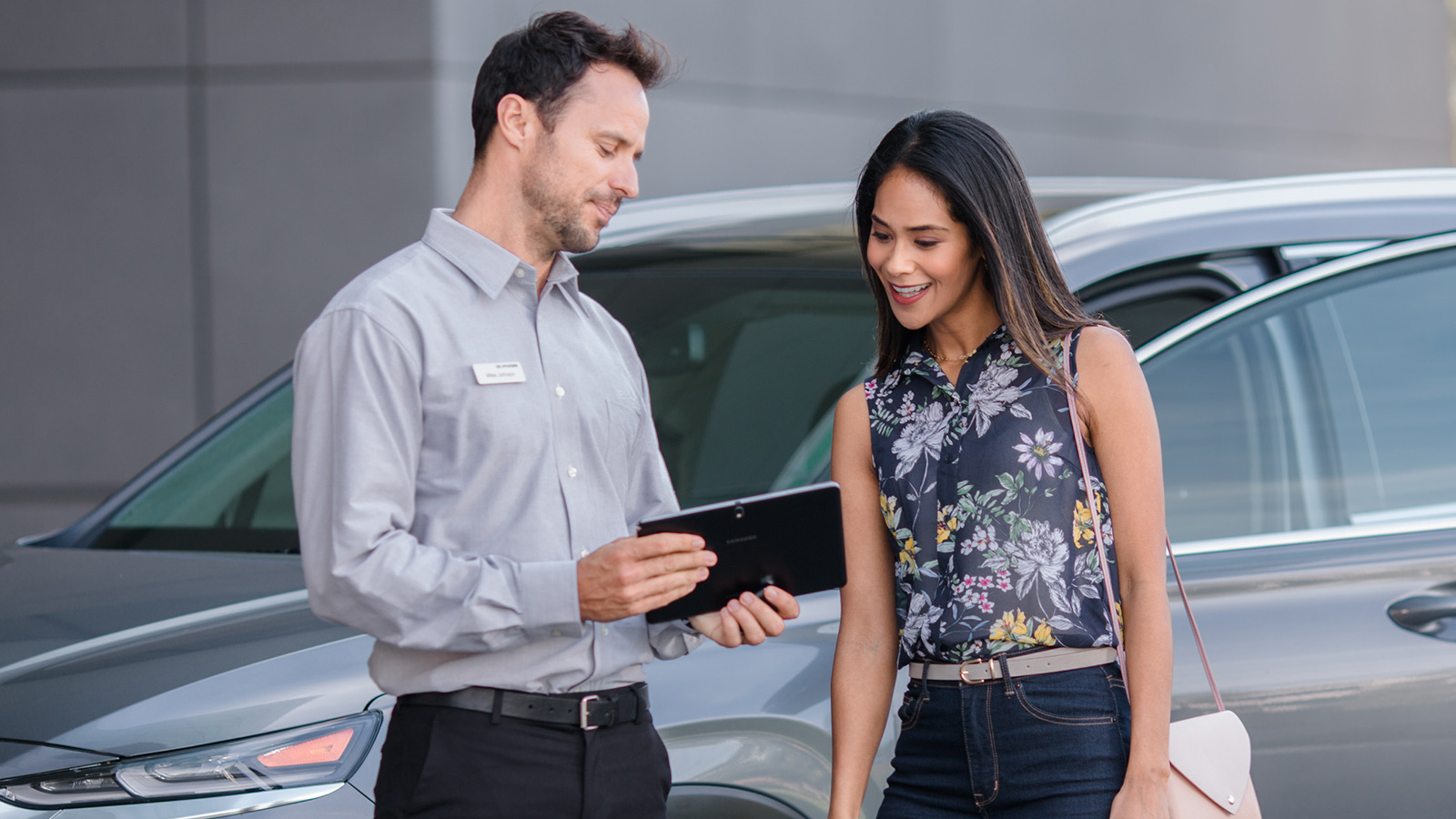 Hyundai technician reviewing a tablet with a customer beside a vehicle