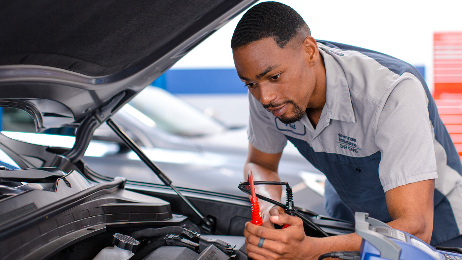Hyundai technician working under the hood of a vehicle