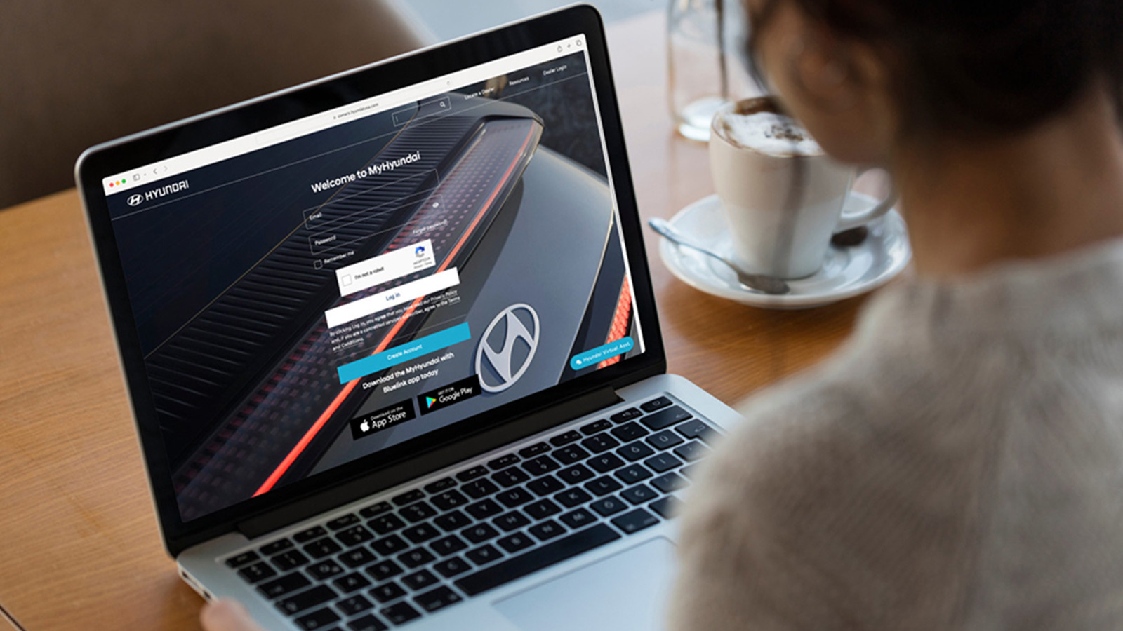 Laptop open to the MyHyundai sign-in page beside a coffee cup