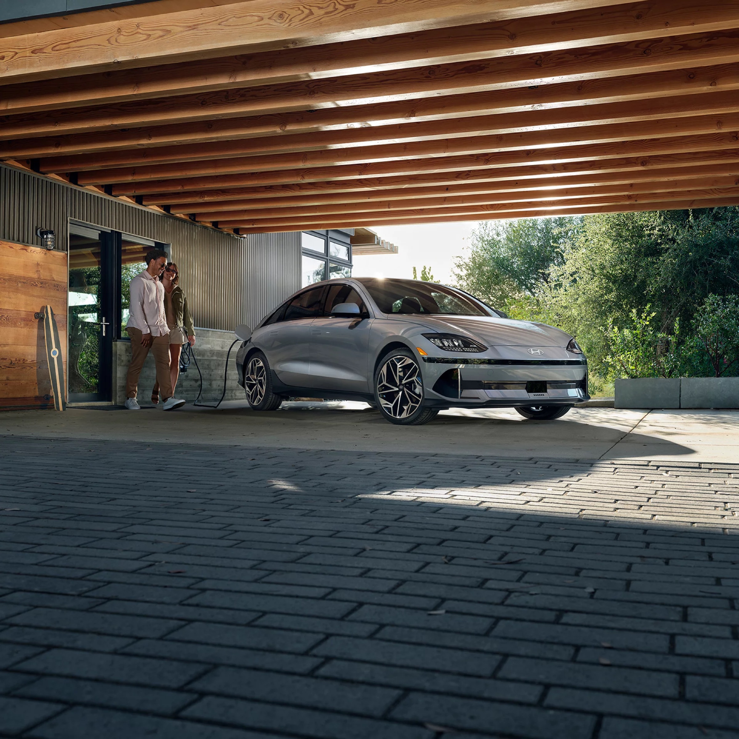 Couple walking toward a Hyundai IONIQ 6 parked under a home carport