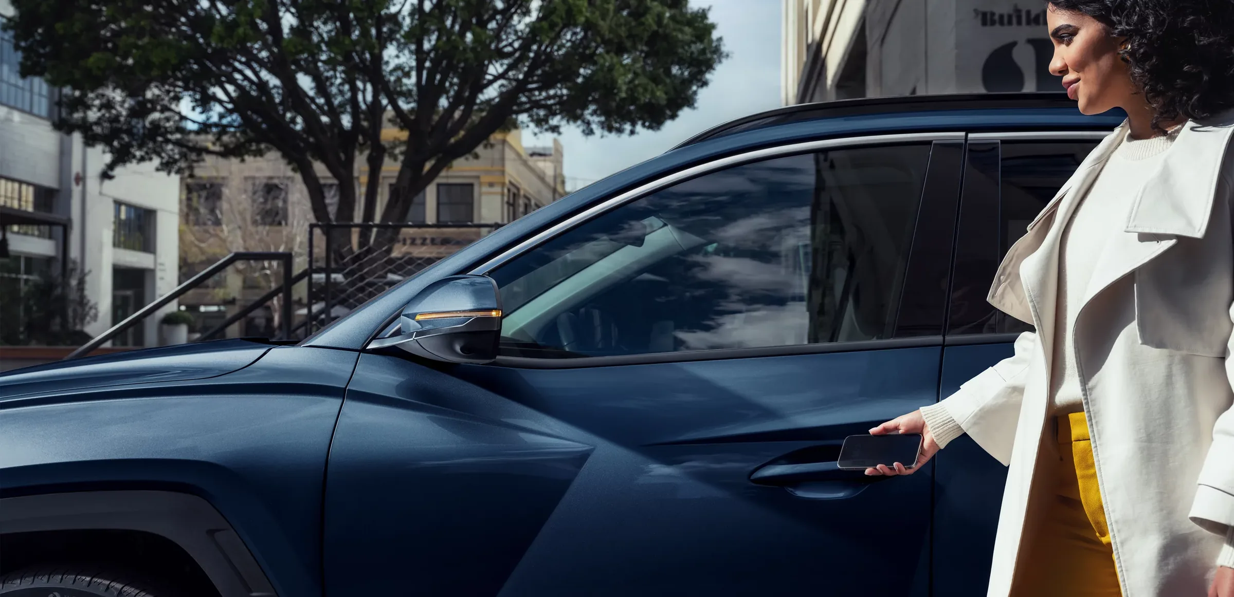 Person unlocking a blue Hyundai Kona with a smartphone