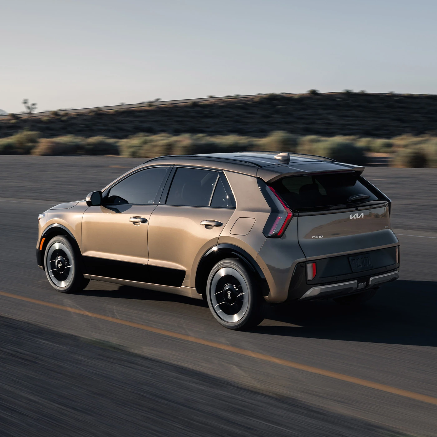 2027 Kia Niro Hybrid driving on a desert road at dusk