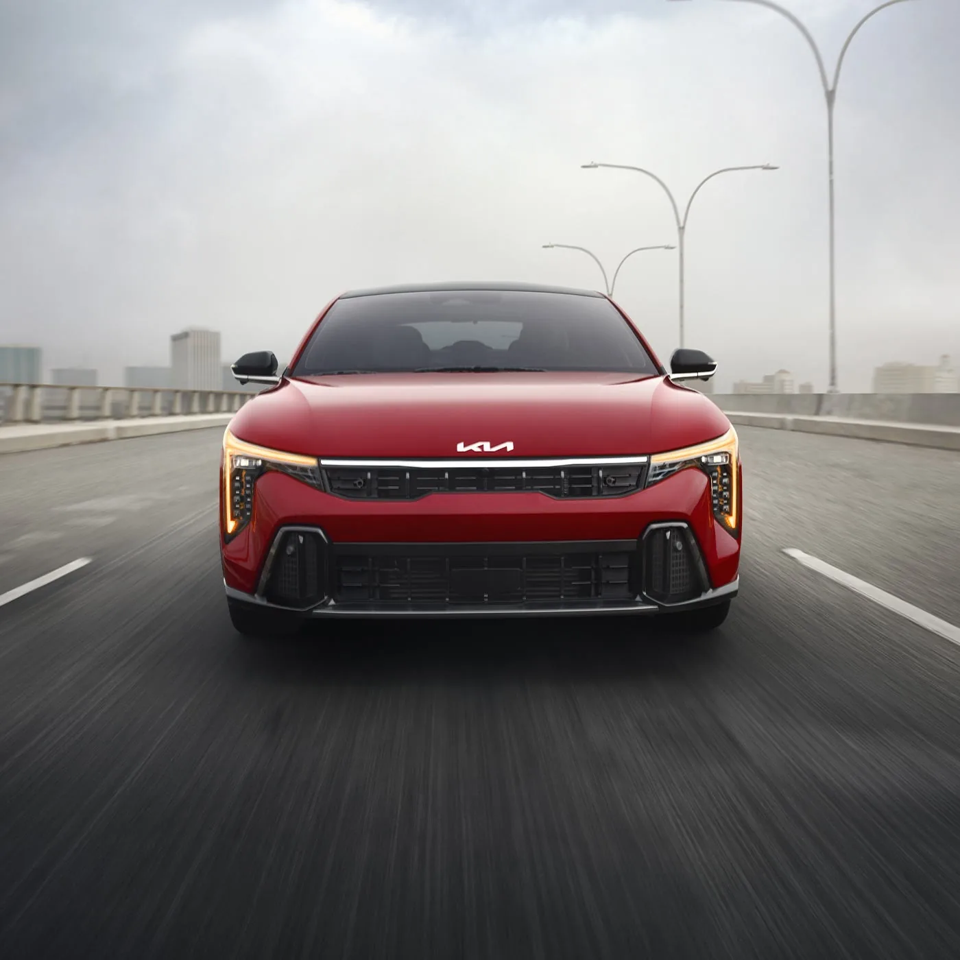 2026 Kia K4 GT-Line driving toward the camera on a city street