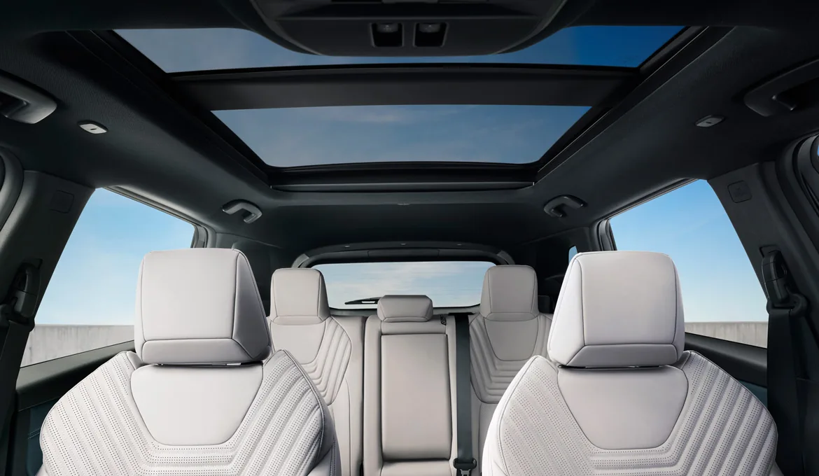 Front cabin of the 2027 Nissan Rogue Hybrid showing light seats, a wide digital display, and a quiet, modern interior.