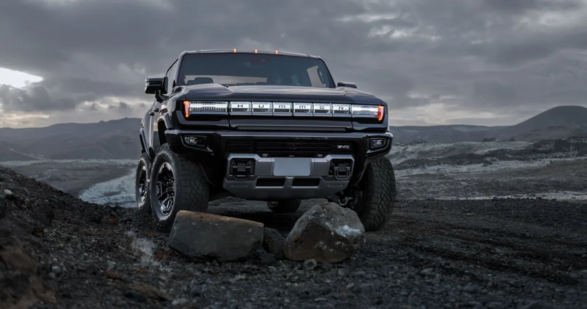 Rear three-quarter view of a GMC HUMMER EV Pickup making a tight turn on desert sand with 4-Wheel Steer