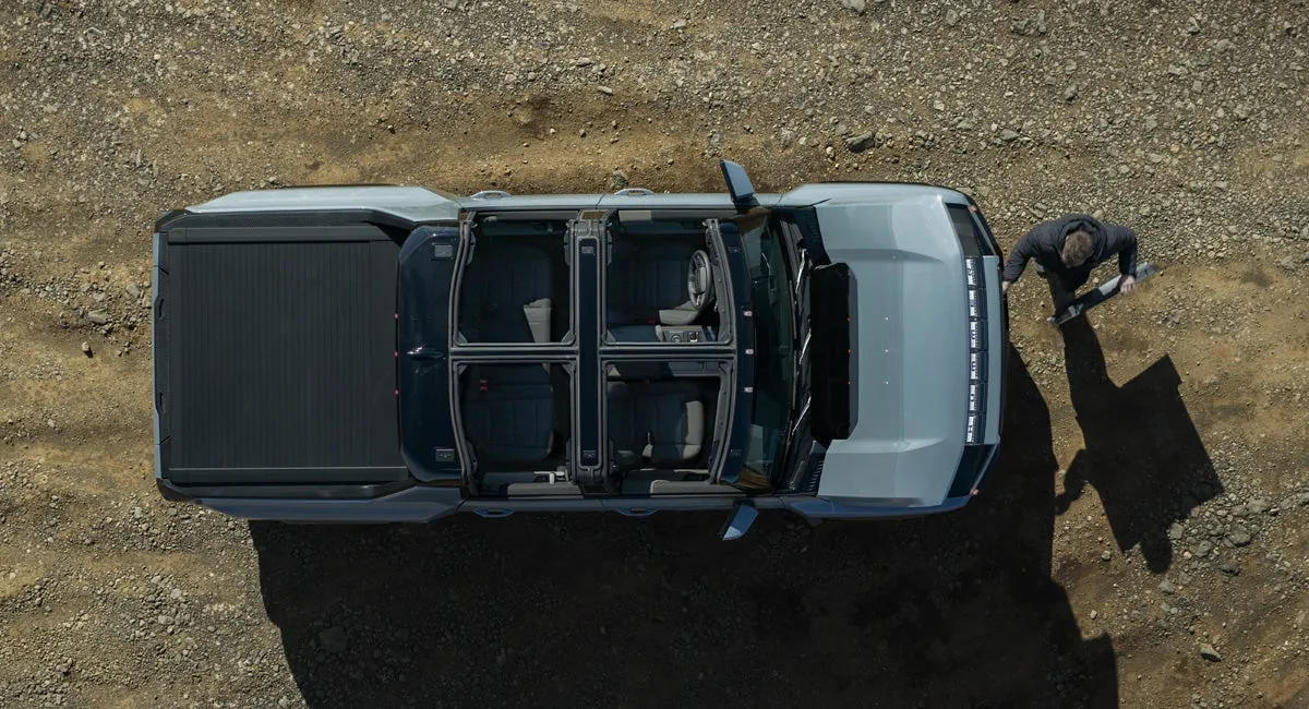 Overhead view of a GMC HUMMER EV Pickup with Infinity Roof Sky Panels removed, parked on a rocky overlook above a desert landscape