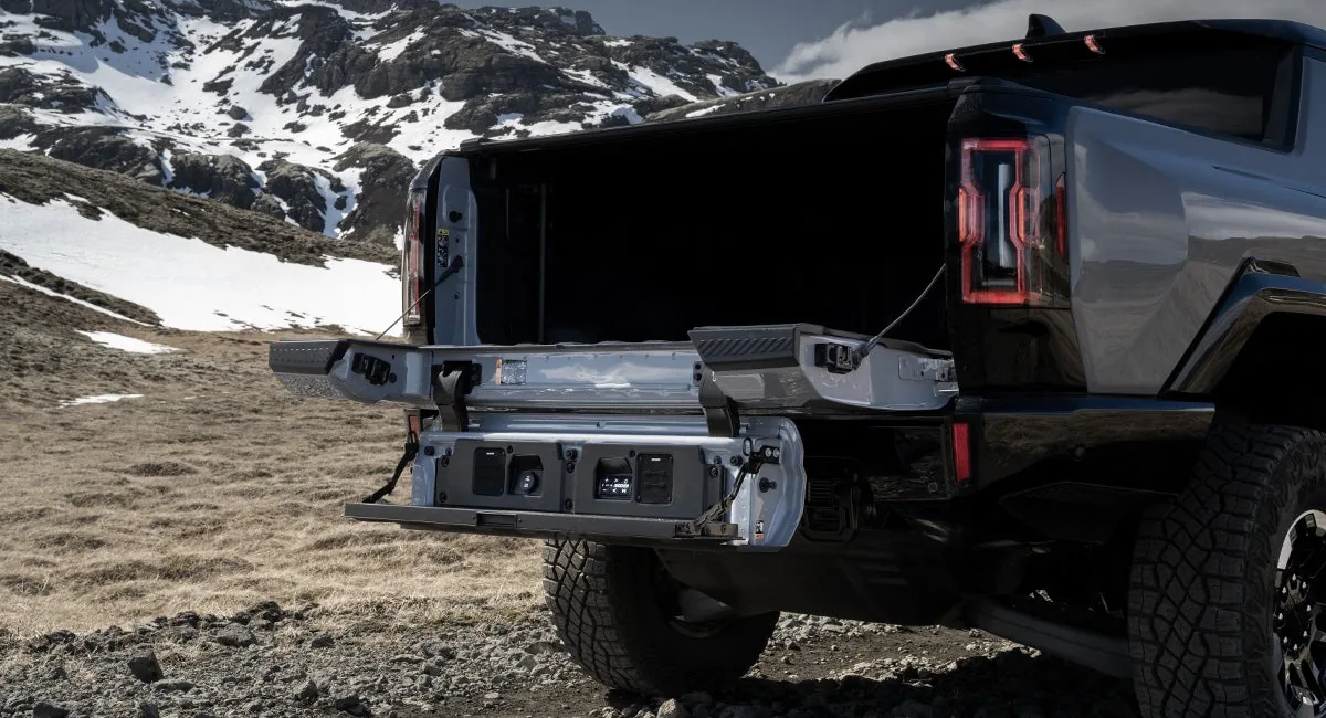 Rear view of a GMC HUMMER EV Pickup with the MultiPro Tailgate folded into a work surface, parked in a desert landscape