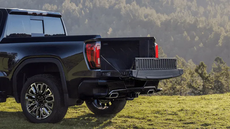 Rear view of a GMC Sierra 1500 parked in a grassy field with the MultiPro Tailgate folded down