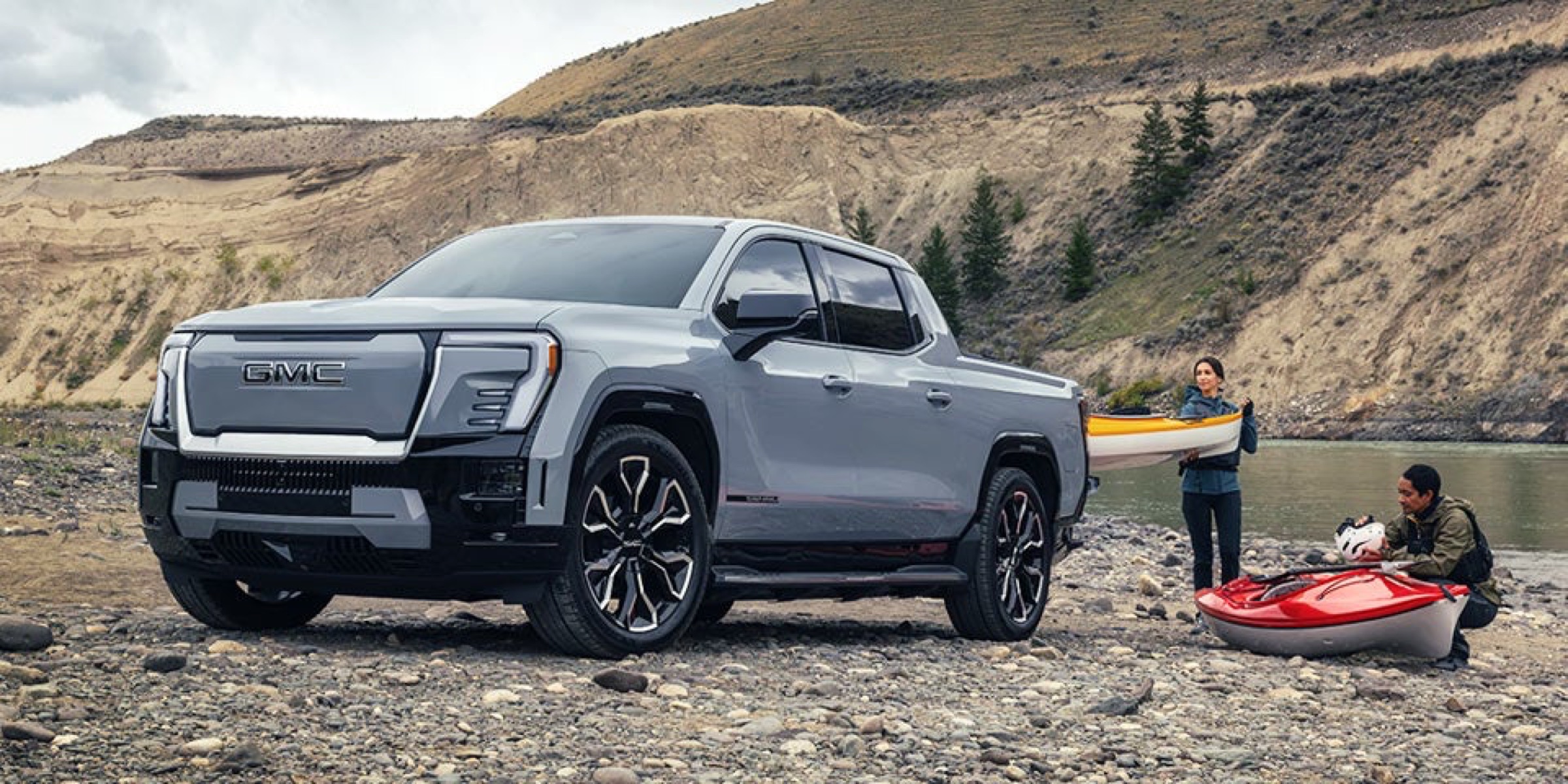 Front three-quarter view of a white GMC Sierra EV Denali in a desert mountain landscape