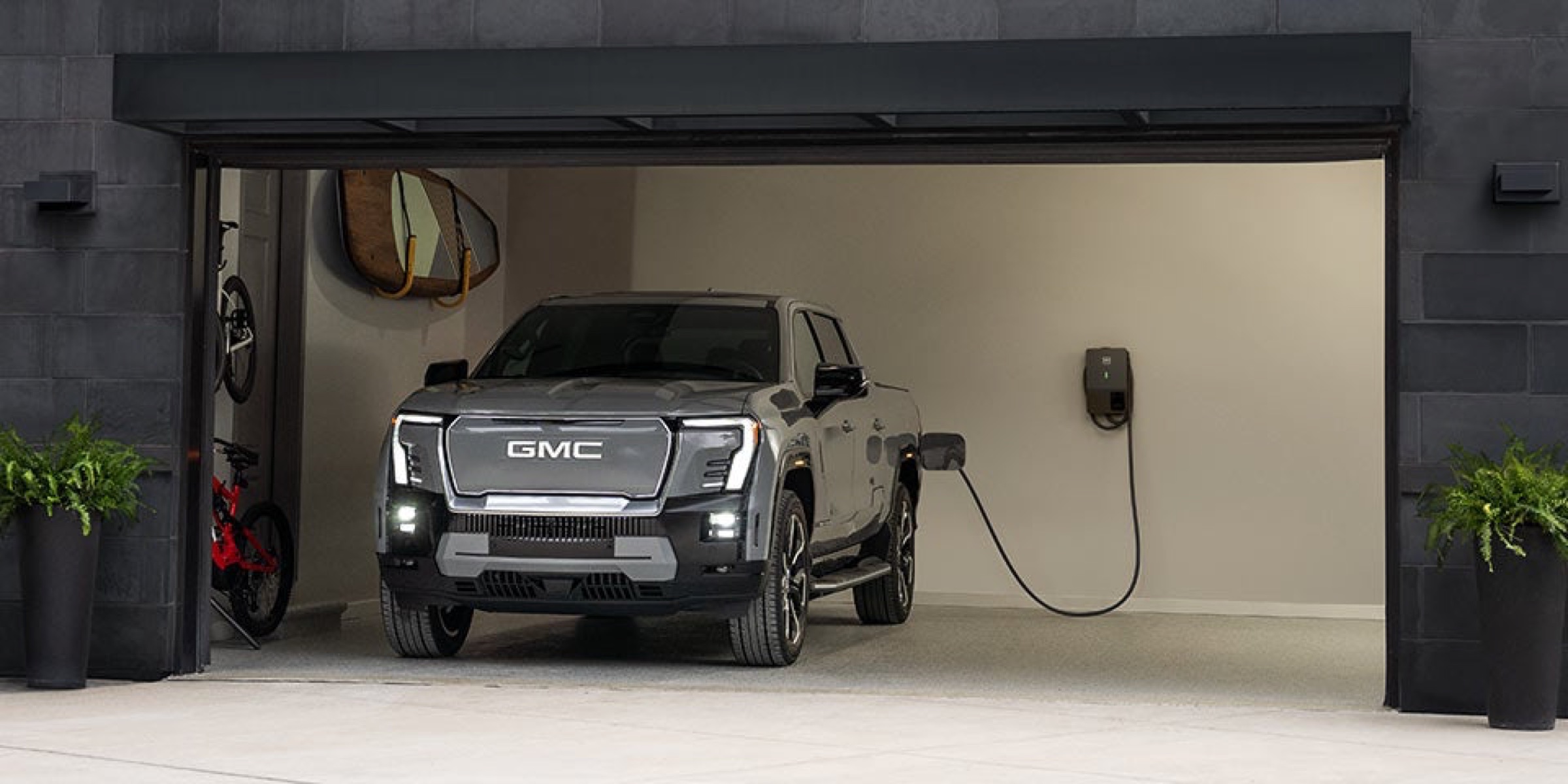 GMC Sierra EV Denali parked in a garage and plugged into a home charging unit