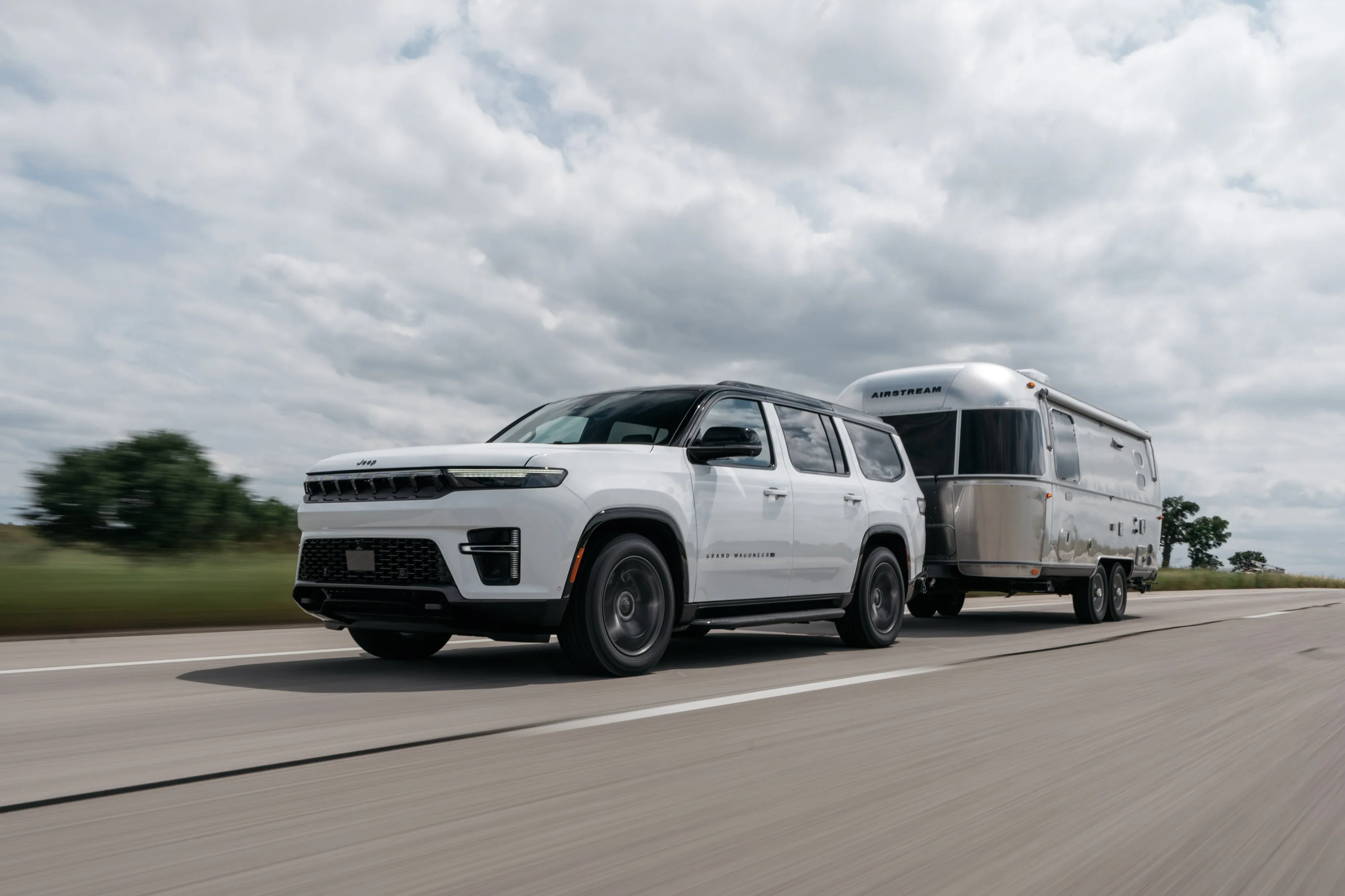 White 2026 Jeep Grand Wagoneer towing an Airstream travel trailer on the highway
